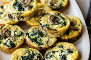 Egg cups with spinach mushrooms and feta on a white platter.