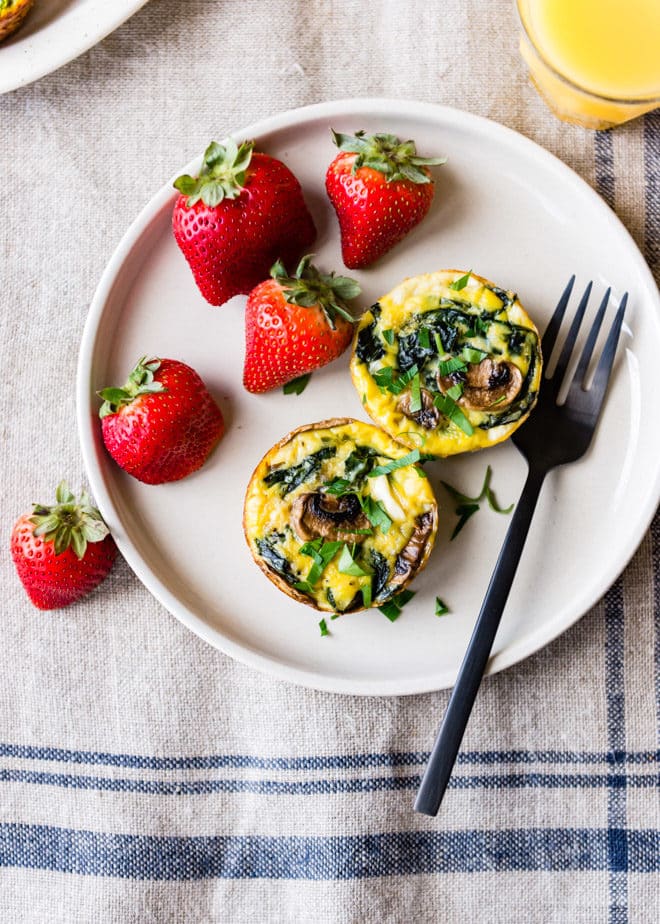 Egg muffins on a white plate with a side of strawberries.