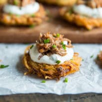 Potato Latkes with Barbecue Pulled Pork on a piece of parchment paper.
