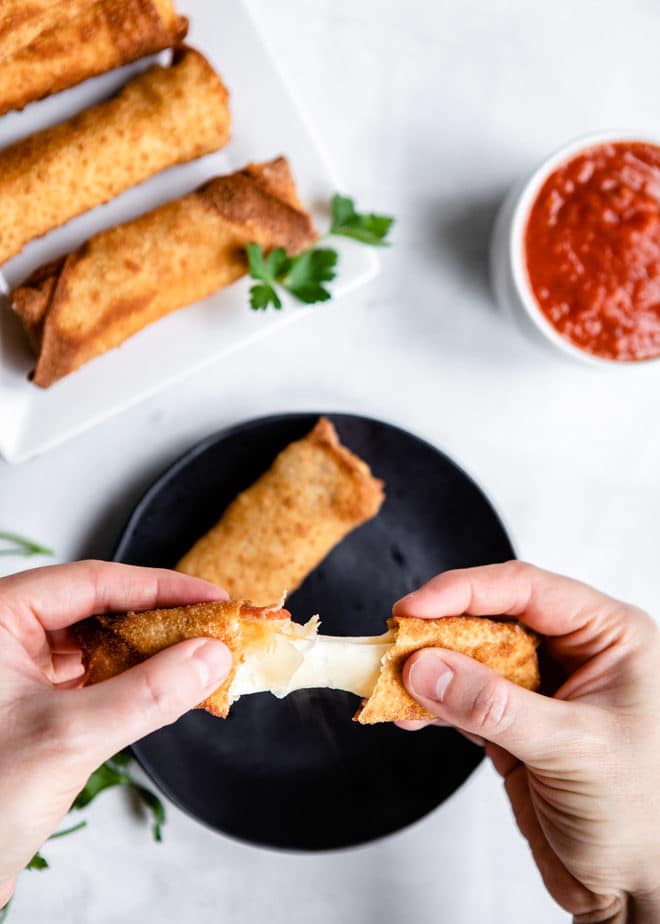 Someone pulling apart a 3-ingredient pizza stick to expose the cheese.