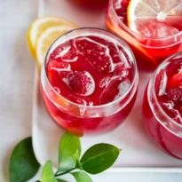 Raspberry lemonade fizz in three clear glasses on a white plate.