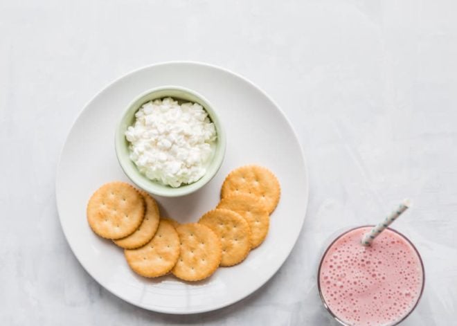 10 Toddler Breakfast Ideas - a photo of seven crackers, tomato slices, a cup of feta cheese, and a pink smoothie on a white plate with a white background - click photo for full written recipes