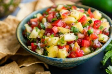 Easy pineapple salsa in a blue bowl surrounded by tortilla chips.