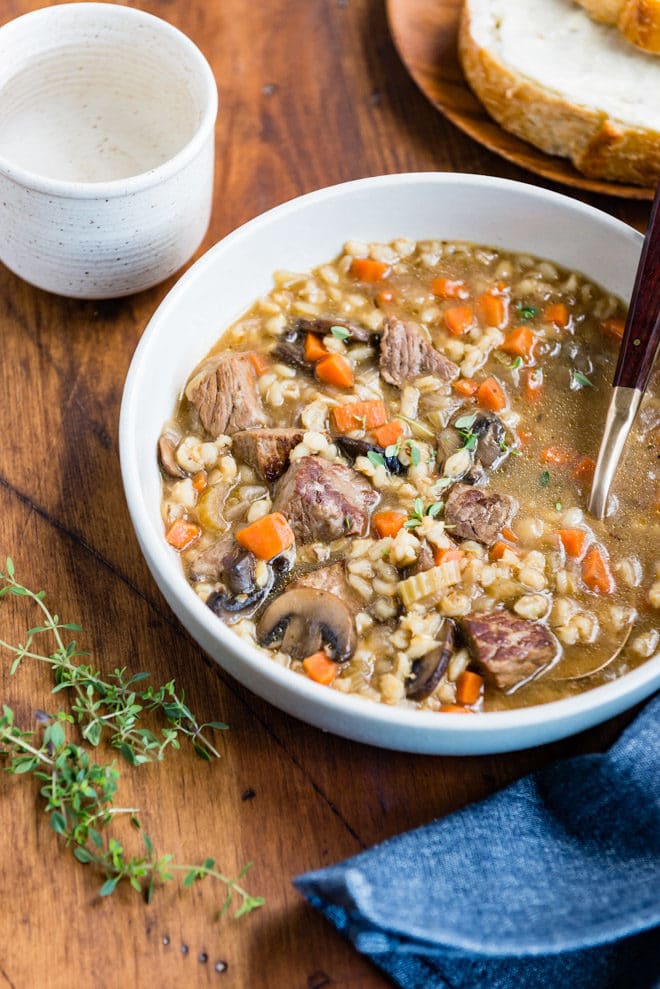Slow cooker beef barley soup in a white bowl.