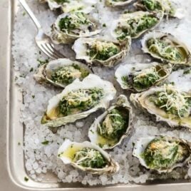 Oysters Rockefeller on a sheet pan with ice.