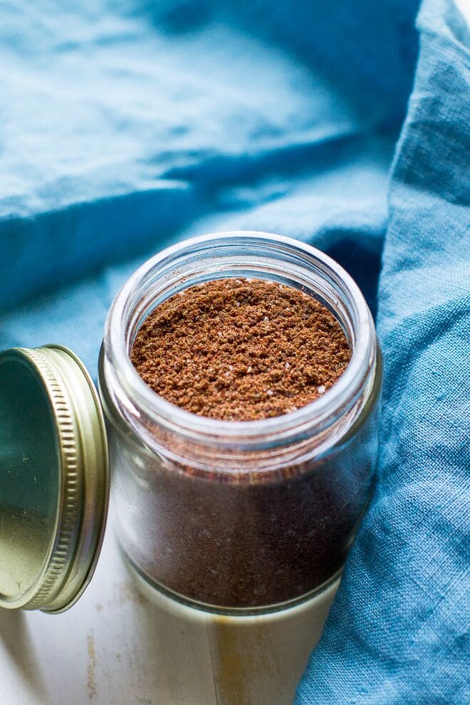 Taco seasoning in a glass jar with a blue napkin around it.