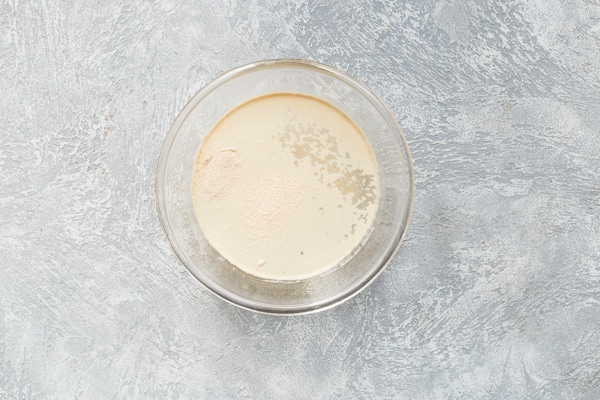Yeast blooming in warm water and sugar in a glass bowl.