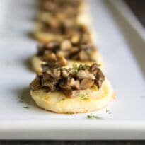 Homemade Cream Cheese Crisps with Mushroom Ragout on a white platter.