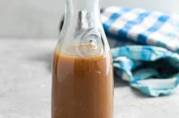 Caramel sauce in a glass bottle on a gray countertop.