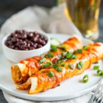 Sriracha Chicken Enchilada on a white plate with a side of black beans.