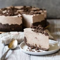 A slice of frosty chocolate cheesecake on a white plate.