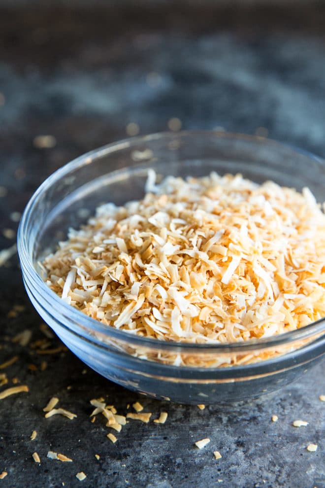 A clear bowl with shredded toasted coconut.