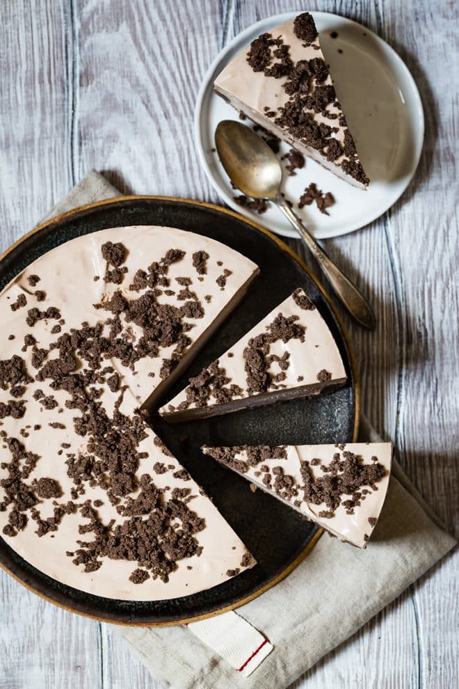 Frosty chocolate cheesecake with three slices cut out.