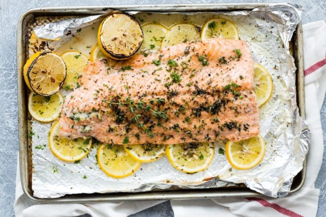 Baked salmon on a bed of lemon slices with fresh herbs.