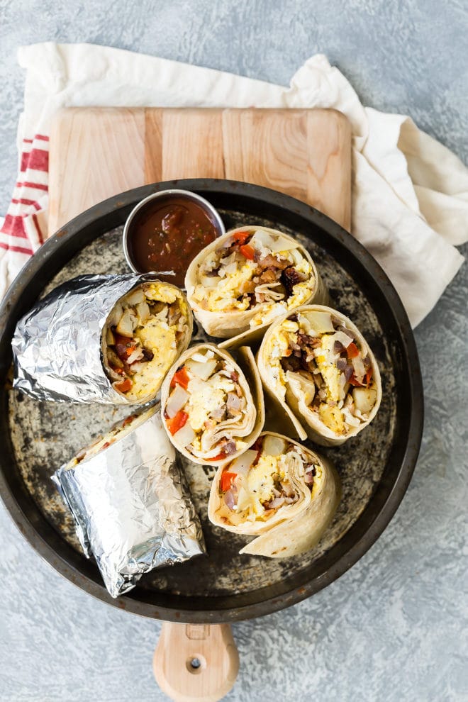 Halved and wrapped breakfast burritos in a black pan.
