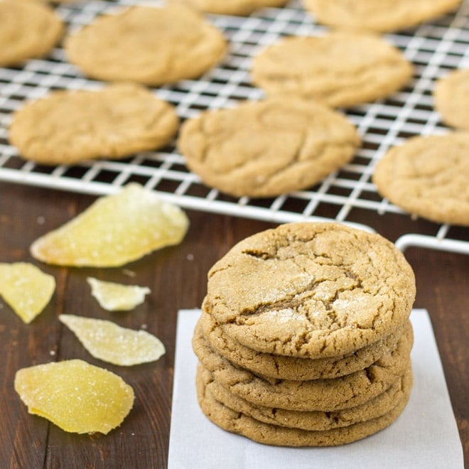 A stack of double ginger cookies with more cookies in the background on a white cooling rack.