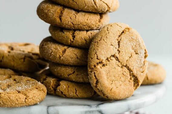 A stack of molasses cookies on a black and white cake platter.