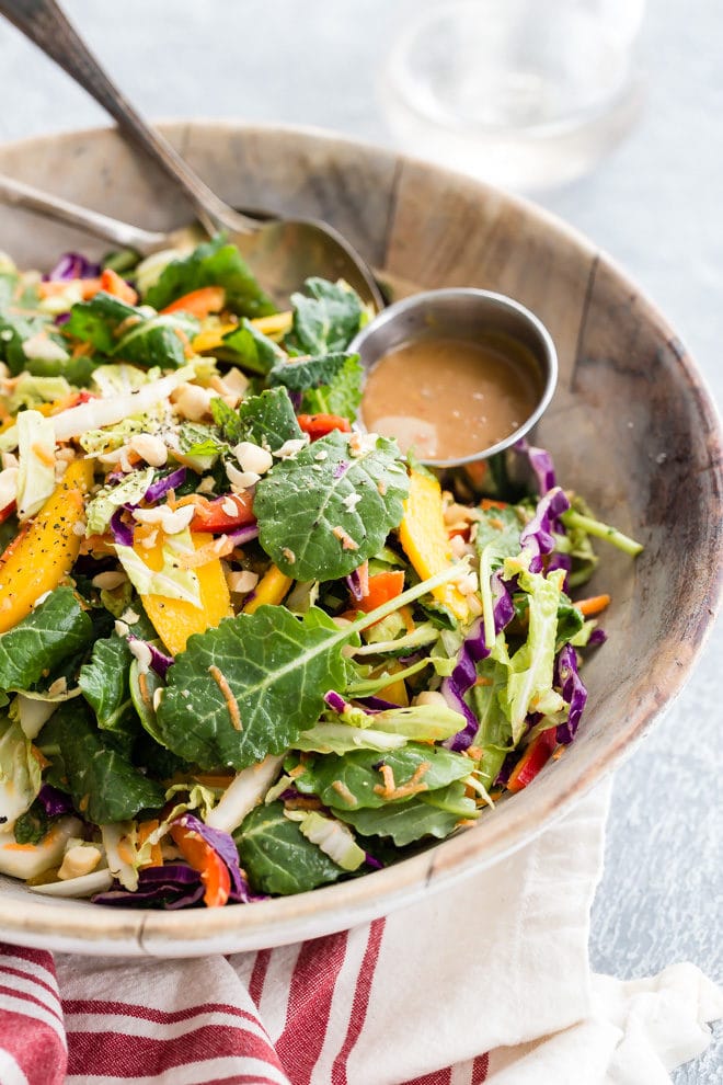 An easy recipe for Rainbow Thai Salad. It's full of colorful vegetables, herbs, sweet mango, crunchy nuts, and a delicious sweet and spicy Peanut Dressing!