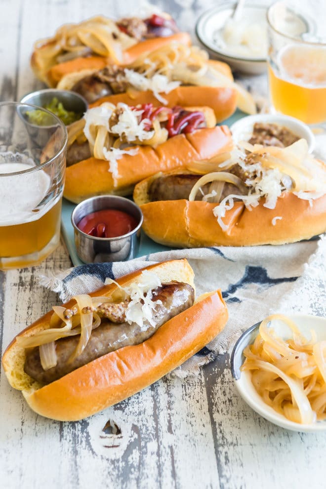 Beer brats with relish, onions, and ketchup on buns.
