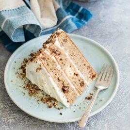 A slice of hummingbird cake on a blue plate with a silver fork.