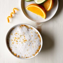 Margarita salt on a white plate with slices of an orange on another white plate.