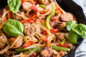 Italian sausage and peppers in a black cast iron skillet.