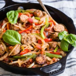 Italian sausage and peppers in a black cast iron skillet.