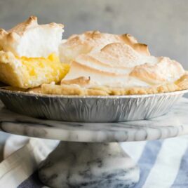 A lemon meringue pie with a piece being lifted out.
