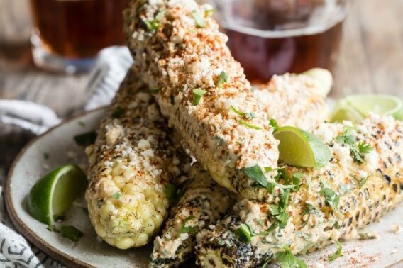Mexican street corn on the cob on a white platter.