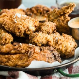 Fried chicken in a silver tray lined with parchment paper.