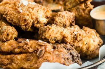 Fried chicken in a silver tray lined with parchment paper.