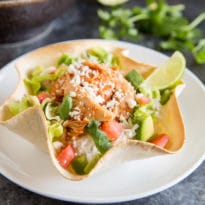 This Chicken Tortilla Bowl recipe makes dinner so easy! Made with slow cooker salsa chicken, rice, and all your favorite toppings, it's fast, fresh, and so delicious! Or, leave out the rice for an easy entree salad for lunch or dinner. Everything can be prepped ahead so dinner is ready in minutes.