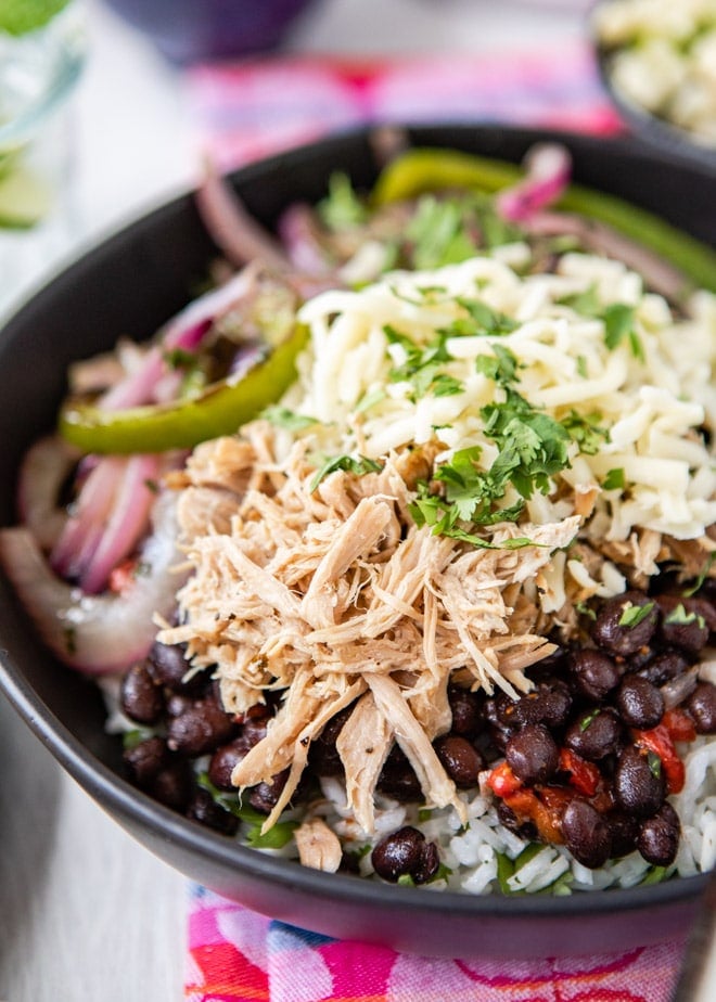 A side shot of chipotle carnitas in a black bowl.