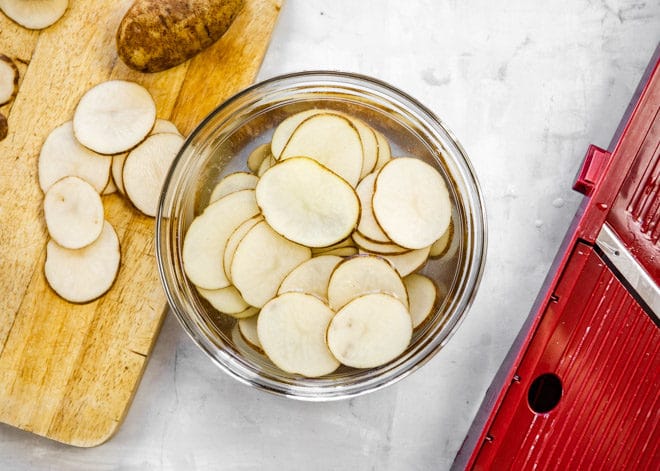 Potato slices in a clear bowl.