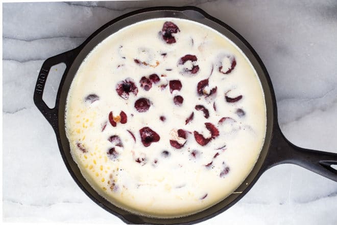 Cherry clafoutis batter in a black skillet.