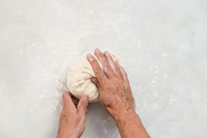 Picture of hands kneading pizza dough.