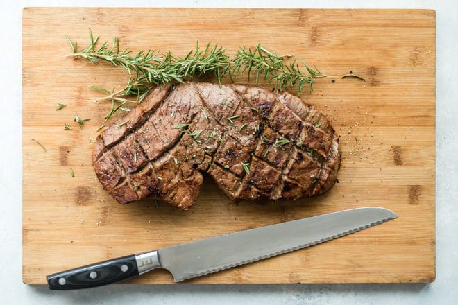 A London broil sitting on top of a wooden cutting board