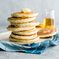 Pancakes in a stack with syrup drizzled on top.