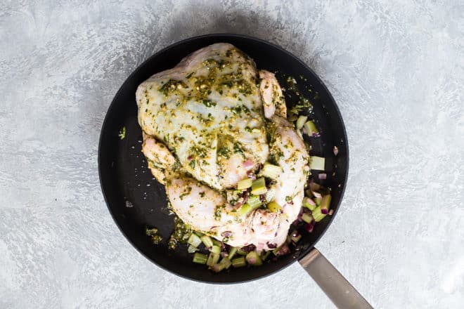 Pesto Roasted Chicken in a skillet with pesto on top  before being cooked.