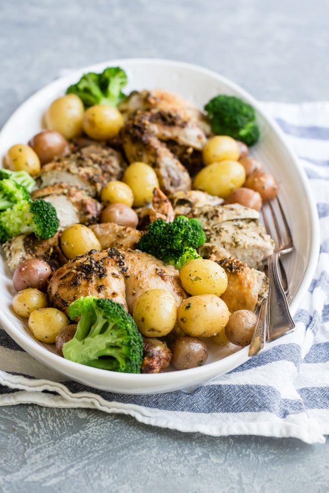 Pesto chicken, potatoes and broccoli in an oval dish.