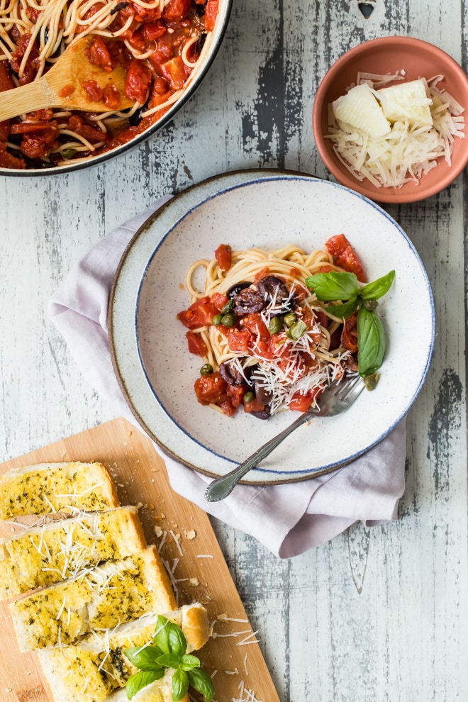 Spaghetti alla Puttanesca: leave it to the Italians to craft a magical dinner out of a little bit of this, and a little bit of that. Garlic, olives, anchovies, tomatoes, and chili pepper come together in this lightning fast recipe that takes eating well to a new level.
