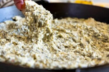 Spinach and artichoke dip in a black cast iron pan.