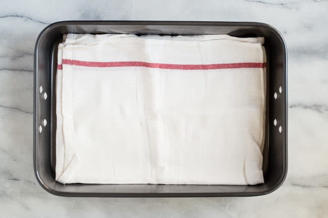 A roasting pan lined with a kitchen towel.