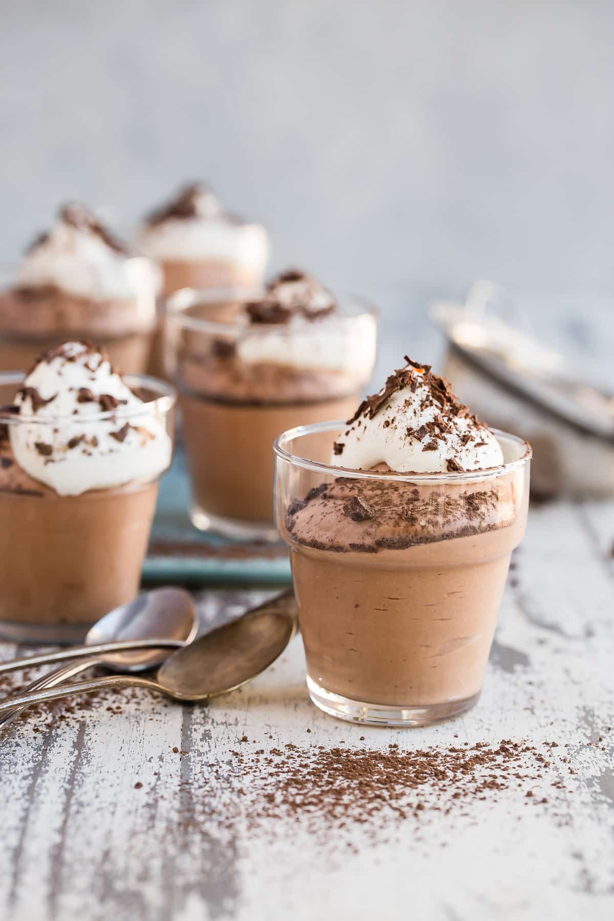Small cups of chocolate mousse next to spoons.