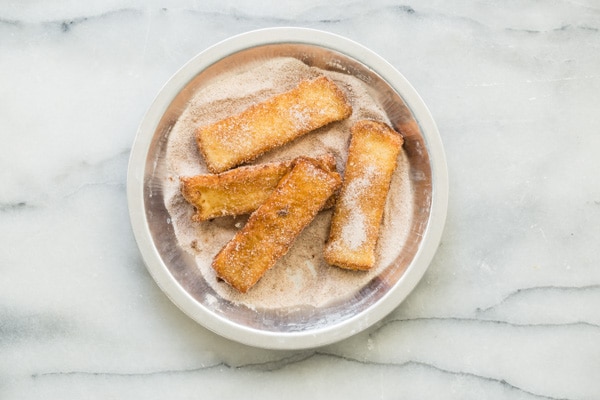 Four French toast sticks in a cinnamon and sugar mixture.