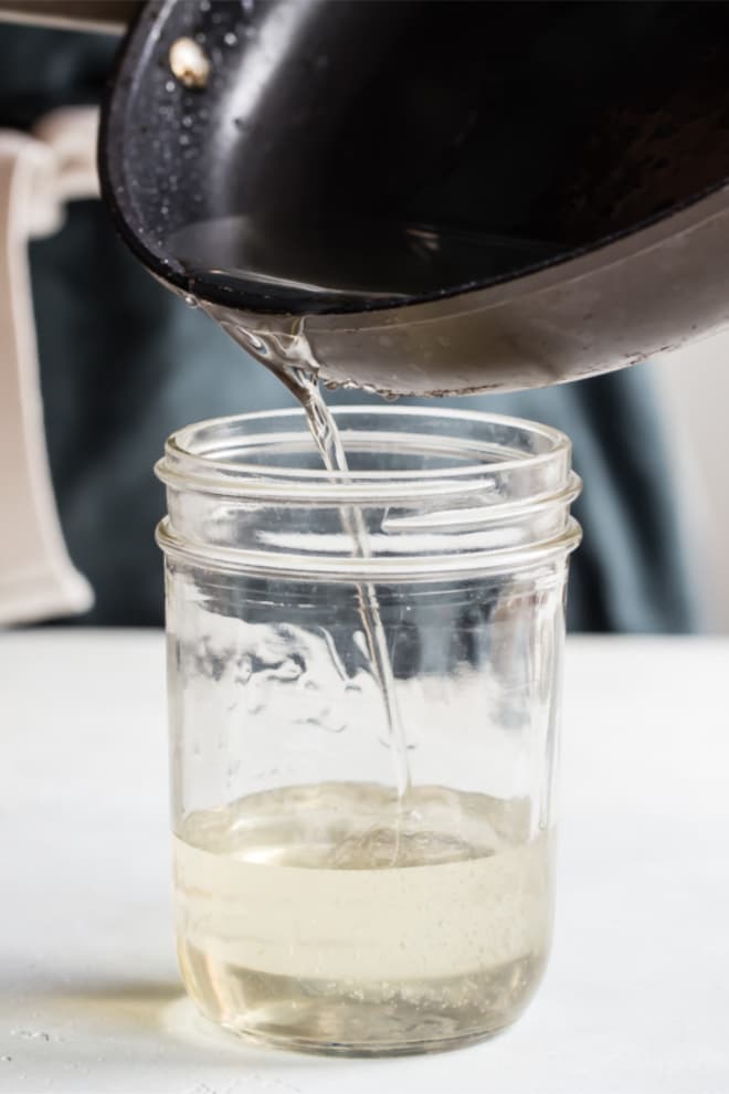 Simple syrup being poured into a glass jar.