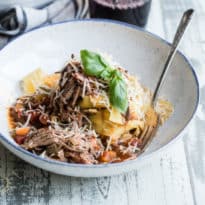 Slow cooker beef ragu with pappardelle in a white bowl with a silver fork.
