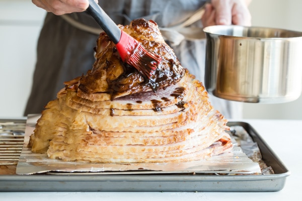 Brushing a baked ham with a mustard and ginger glaze.