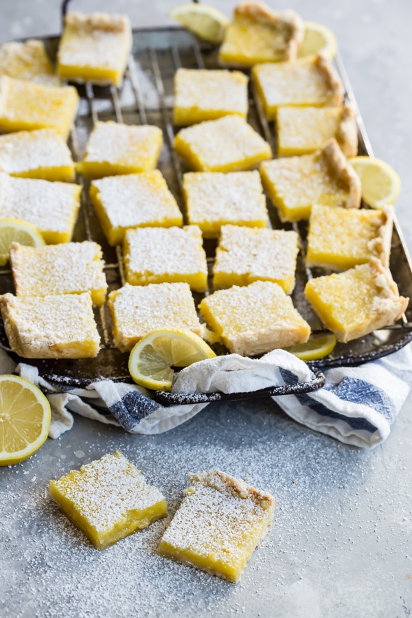 Lemon bars cut into squares on a baking sheet.