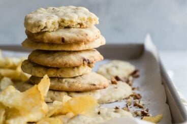 Potato chip cookies stacked on a baking sheet.